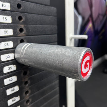 10 mm GymPin cable stack extender attached to a weightlifting machine, with visible branding and a turning knob.