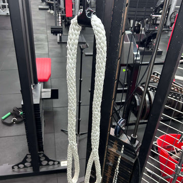 White resistance band hanging on a gym machine with gym equipment in the background