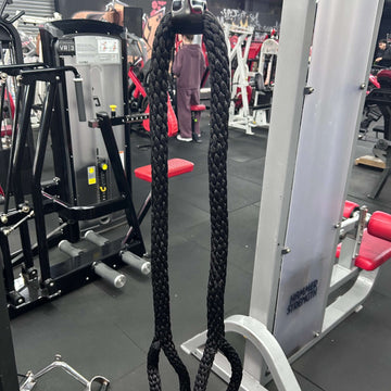 Black rope attached to a gym machine with gym equipment and people in the background