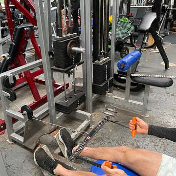 A person using a cable machine in a gym setting using a KingPin to increase the load they are working out with.