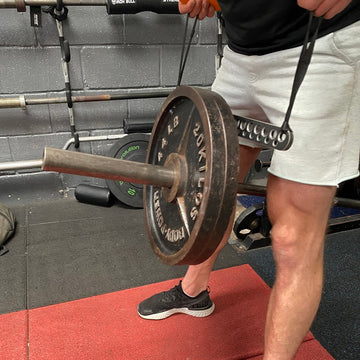 Person lifting a barbell with weights on a red platform in a gym setting