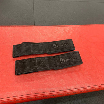 Two black gym straps on a red and gray mat