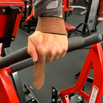 Hand wearing a brown wrist support brace in a gym setting