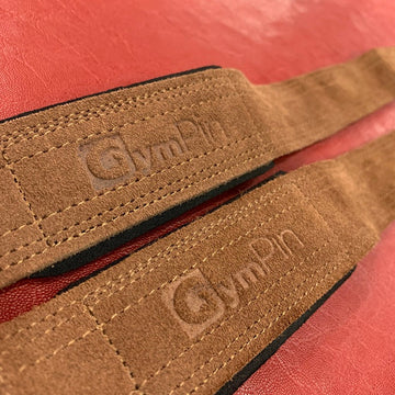 Close-up of a brown leather strap with 'GymRat' branding on a red background