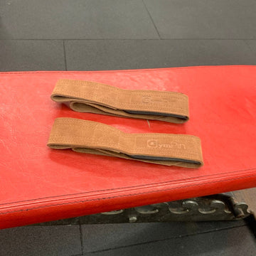 Two brown resistance bands on a red surface with a gray floor background