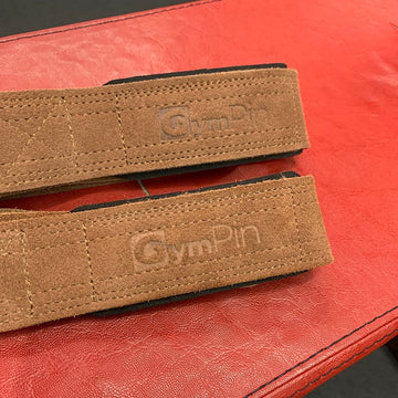Two brown straps with 'GymPin' branding on a red surface