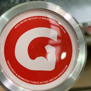 Close-up of a metal weight with a red label and visible branding.