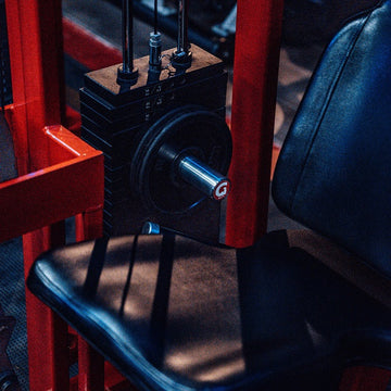 A close-up image of the 10mm Original 2" GymPin cable stack extender fitted on a gym machine, showing its metallic construction and the small end of the extender.