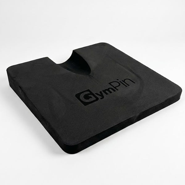 GymPin hamstring pad featuring a contoured cut-out and dense black foam design, used to increase range of motion and provide support during hamstring curl and glute training.