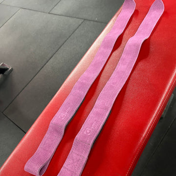 Two pink resistance bands on a red surface with a blurred background