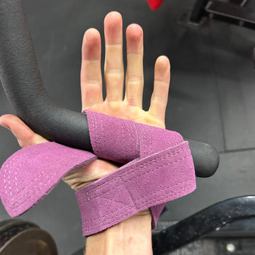 Hand with purple wrist wrap holding onto a steering wheel