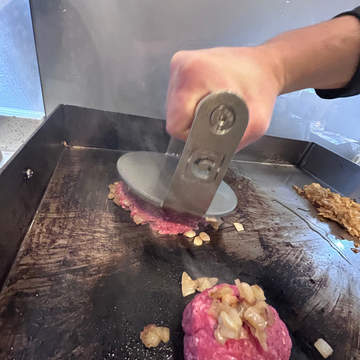 Person using a Burger Patty Press on a patty on a grill