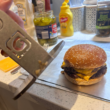 Hamburger being measured with a ruler on a kitchen counter, with condiments in the background.