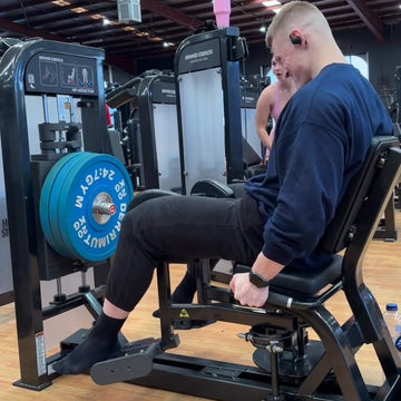 Person using a weight machine in a gym with weights on the machine.