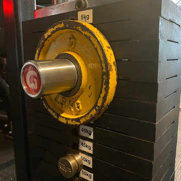 A 2 inch GymPin MiniPin attached to a cable machine weight stack, with a black background and yellow details.
