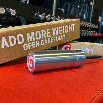 The Original GymPin displayed on a gym bench with packaging, designed for progressive overload in strength training.