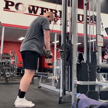 A person using The Original GymPin on a cable machine at the gym, focusing on progressive overload training.