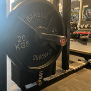 Extra-long version of a gym pin placed in a weight stack of a gym machine, showing a 20 kg barbell plate attached to the end.