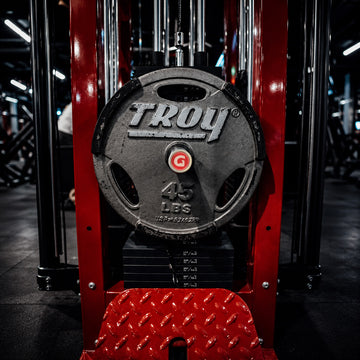 Troy weight plate on a red weightlifting machine in a gym setting witha  GymPin