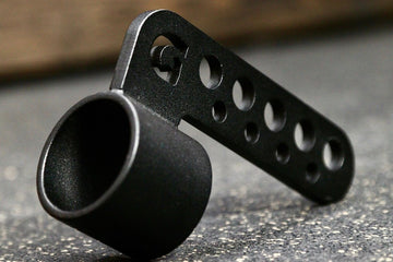 A black belt squat collar attachment designed to be used with a barbell, featuring multiple holes for height adjustment.