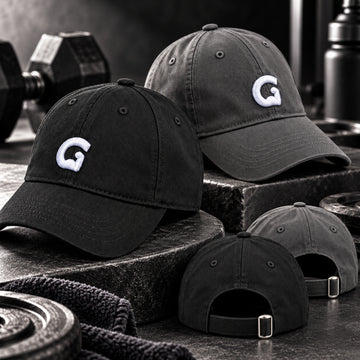 Black and grey GymPin baseball caps styled in a premium gym setting