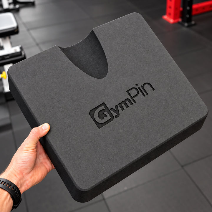 GymPin hamstring pad held in one hand, showing its profile and cutout