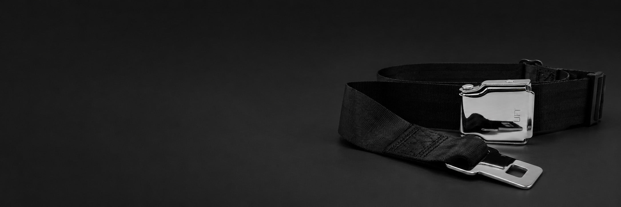 Black seat belt with silver buckle on a black background