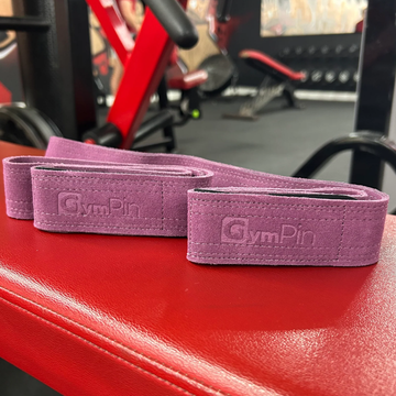 Purple resistance bands with 'GymPin' branding on a red surface, gym equipment in the background.