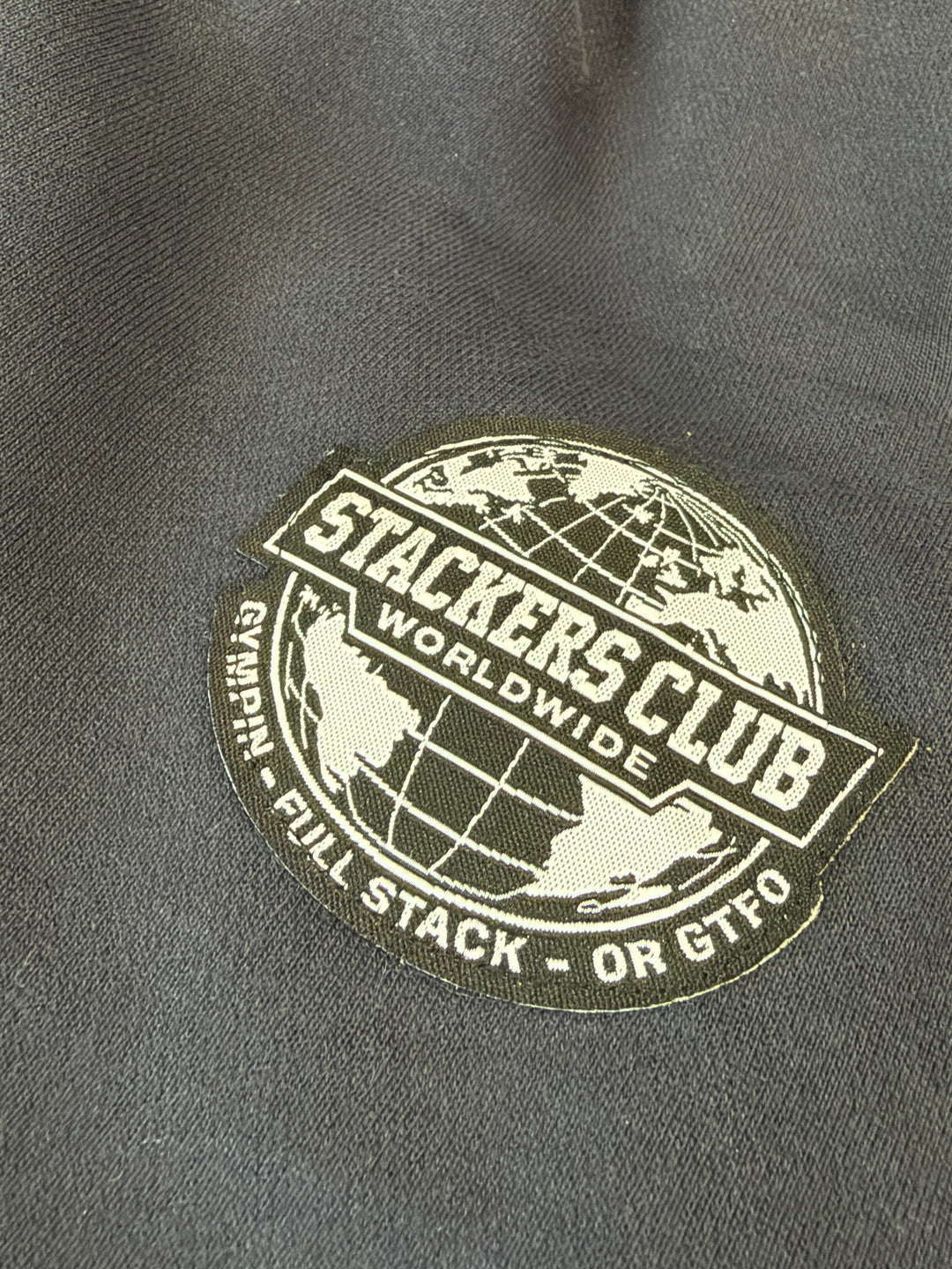 Close-up of the sewn STACKERS CLUB Worldwide woven badge
